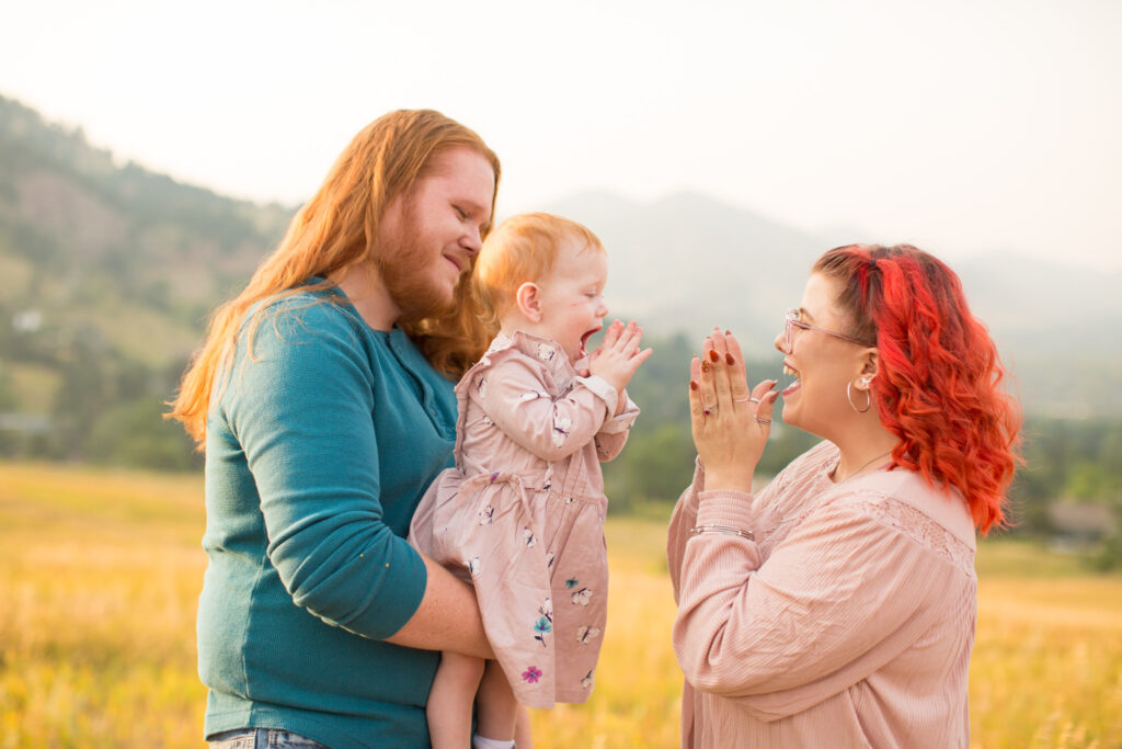 A family of three clap together during their session at Chautauqua Park in Boulder, Colorado