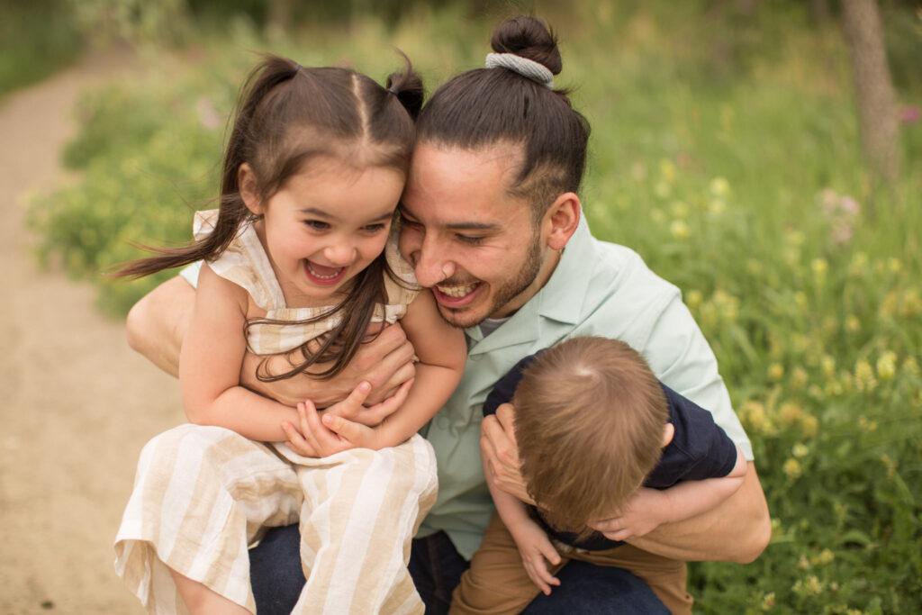 A father plays with his young son and daughter during their family photos in Boulder, Colorado.