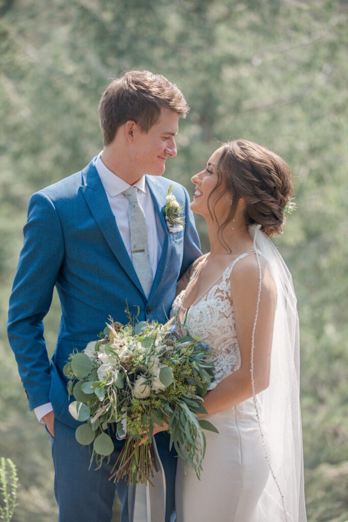 A couple gaze at each other, the bride holds her bouquet during their first look at The Woodlands