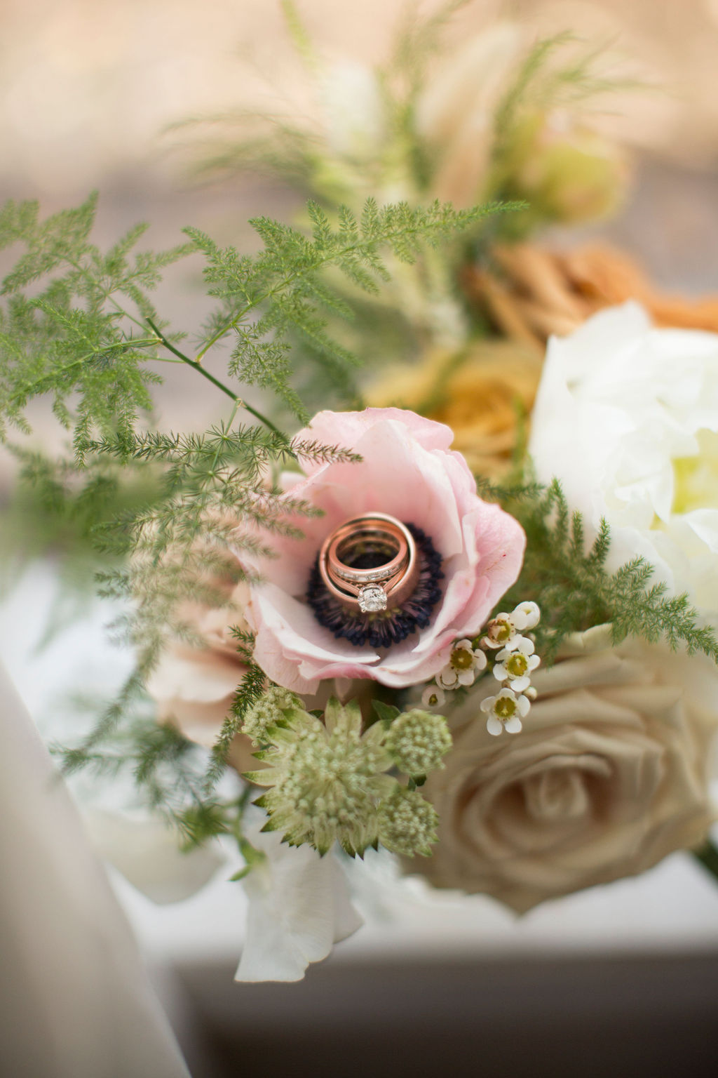 Details of wedding rings stacked in the center of a pink flower in a bouquet at a boulder sunrise amphitheater wedding