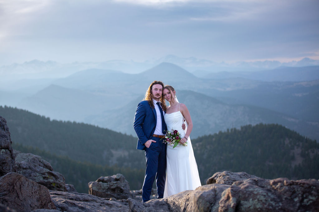 A bride and groom stand together with heads touching in the mountains while eloping in boulder