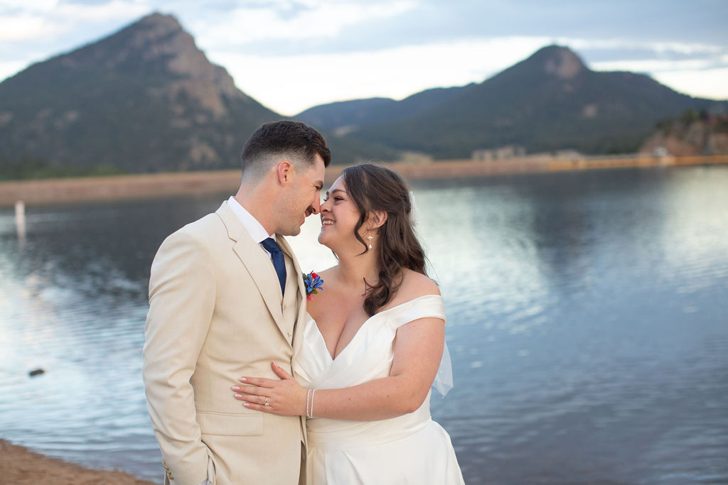 Newlyweds laugh and boop noses by a lake during their rocky mountain national park elopement