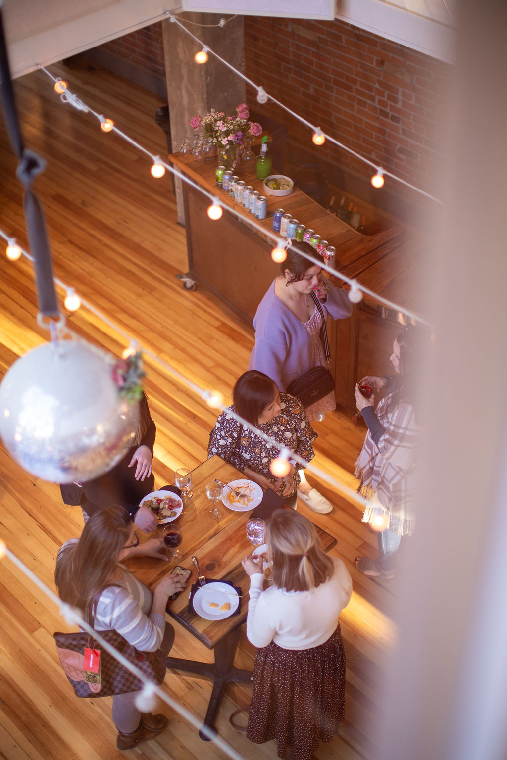 A look down through the market lights at guests mingling with snacks and drinks