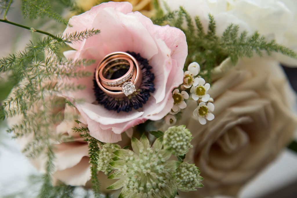 Details of rose gold wedding rings in a pink flower from a bouquet