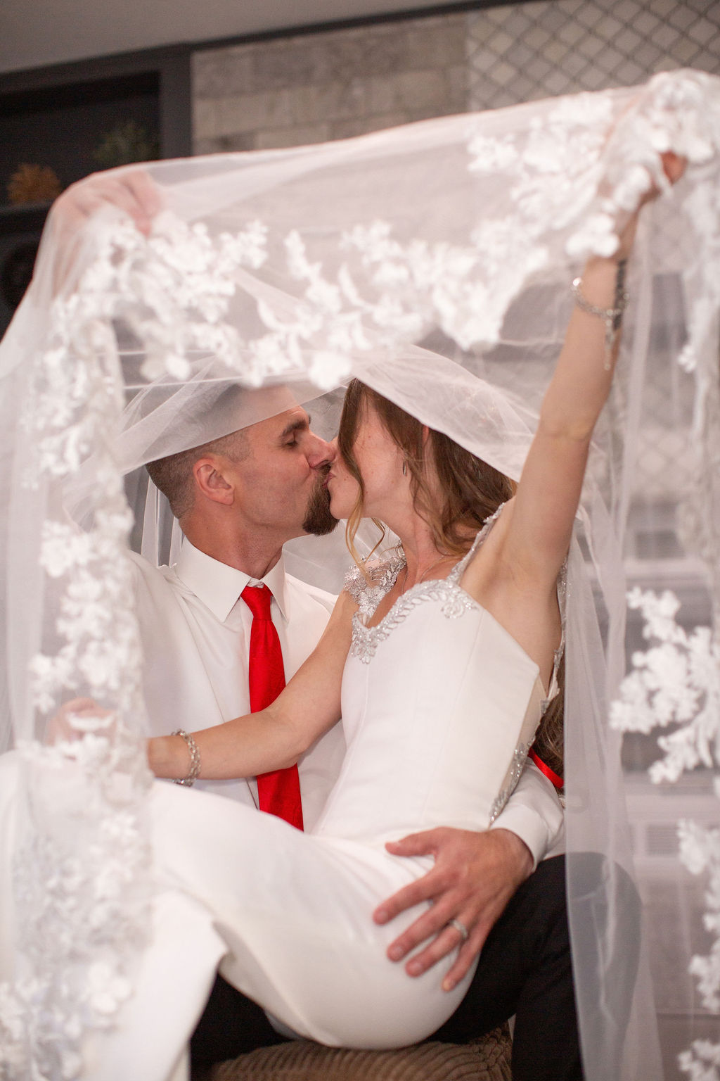 A bride sits in the lap of her groom while they kiss under the veil after enjoying colorado elopement planners