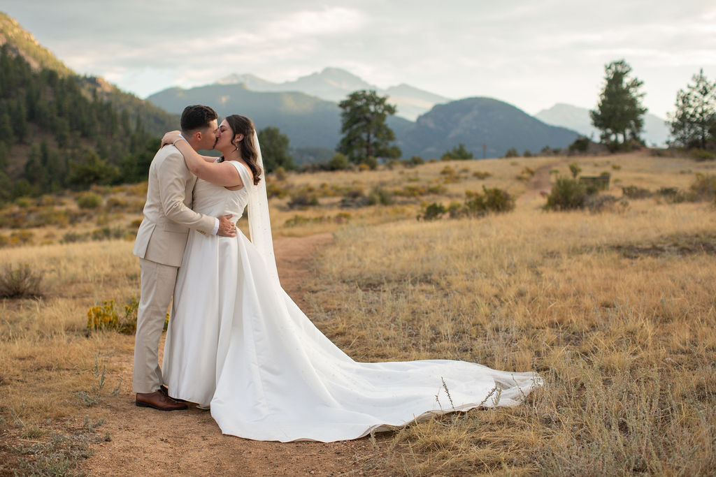A bride and groom kiss in a meadow at sunset in the mountains while they elope in Estes Park