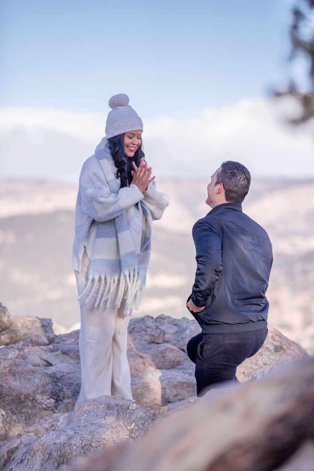 A woman says yes to her now fiancee as he proposes on a mountain hike