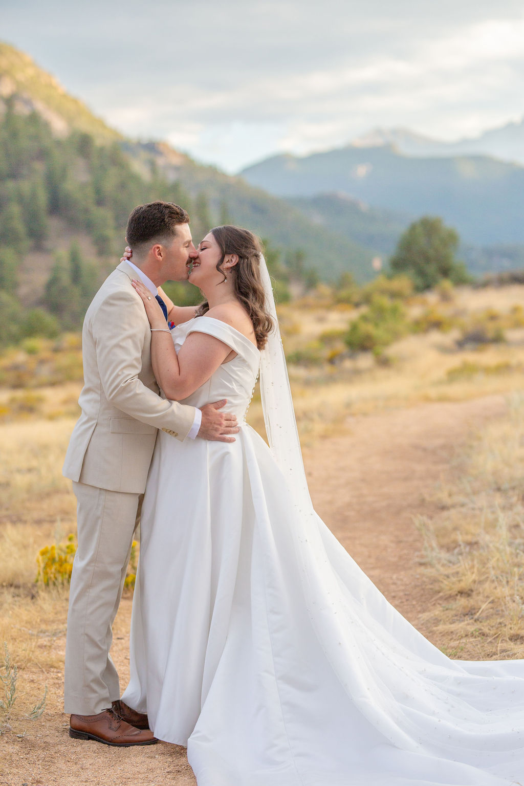 A bride and groom share a happy kiss in a mountain trail at sunset at one of the micro-wedding venues in colorado