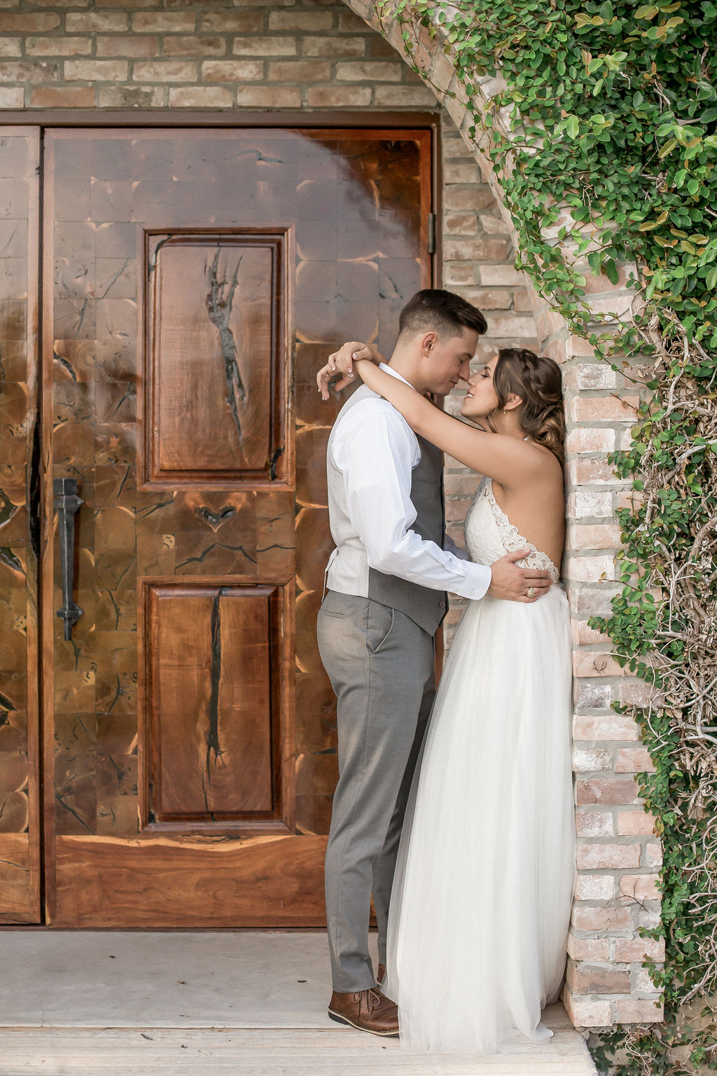 A bride and groom lean in for an intimate kiss against a brick wall at a main entrance to one of the small wedding venues in Boulder, CO