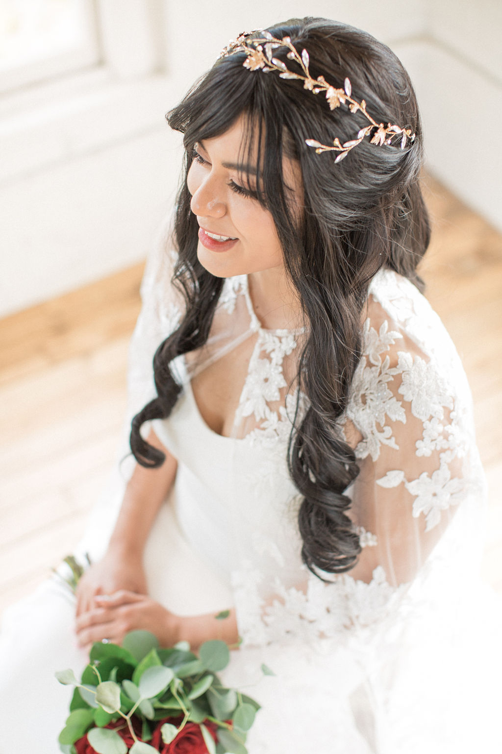 A look down at a bride sitting under windows with a lace coverup and gold hair piece at one of the wedding venues in Loveland, CO