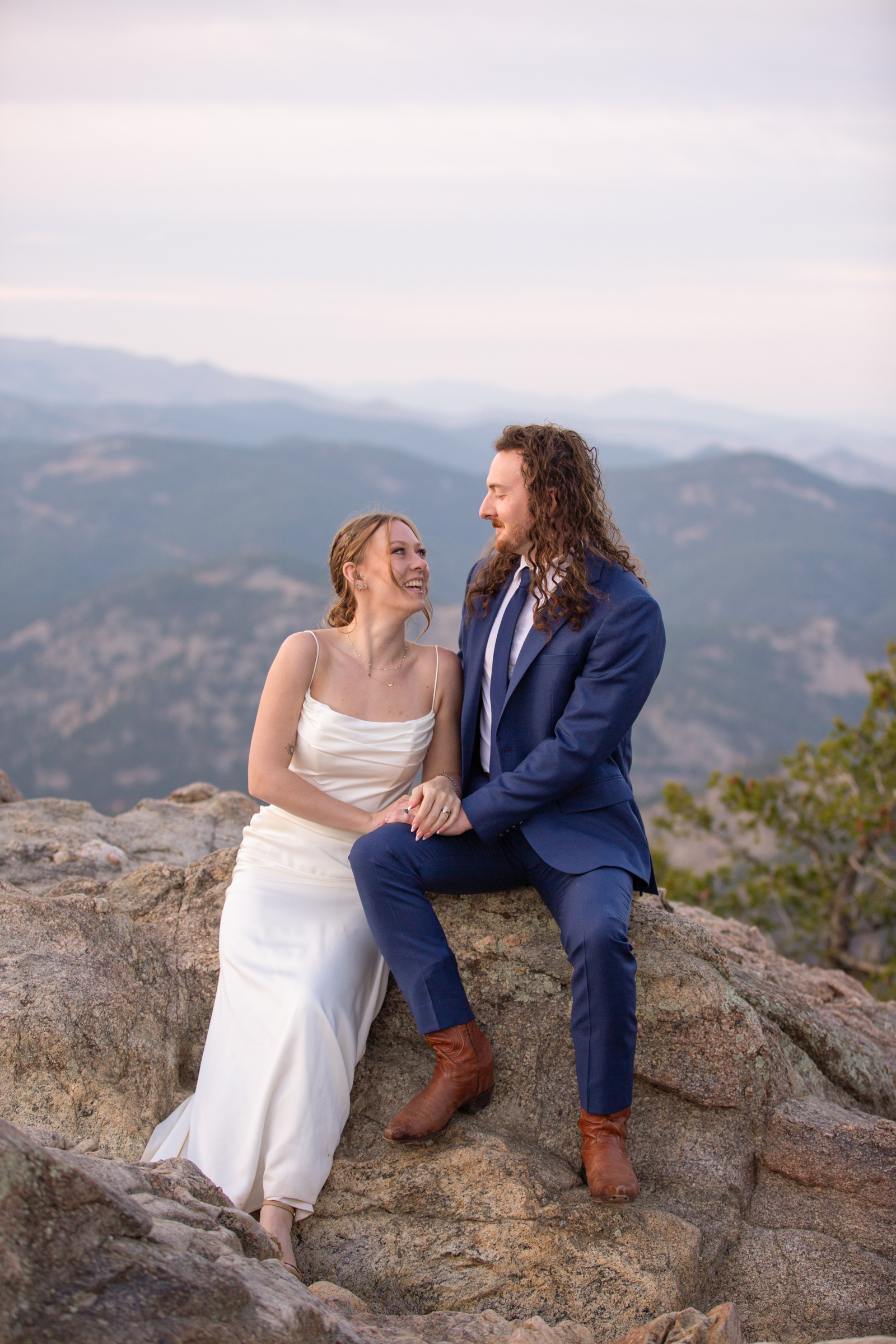 Newlywed couple embracing at a scenic overlook with epic mountain views in Rocky Mountain National Park.