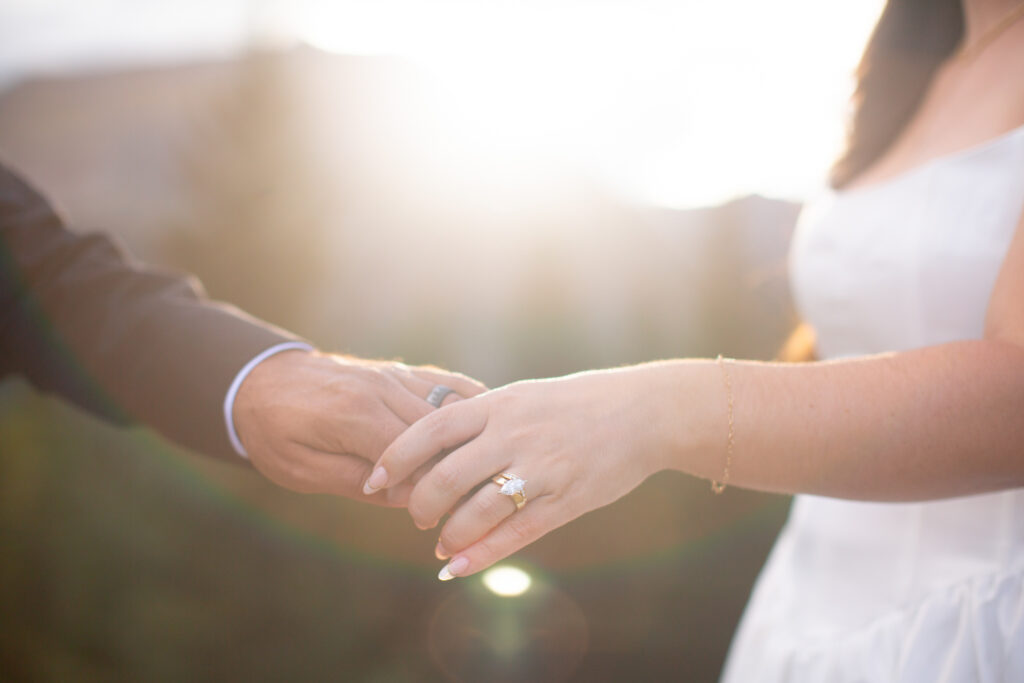 Close-up of newlywed couple holding hands with wedding rings visible during their Breckenridge elopement
