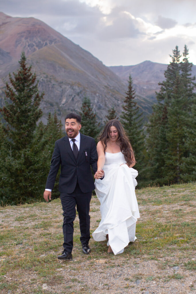 Couple running toward the camera with a dramatic Colorado mountain backdrop during their Breckenridge elopement
