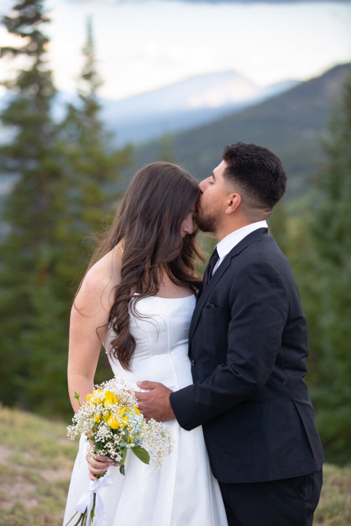 Groom kissing his bride on the forehead during their Colorado mountain elopement near Breckenridge

