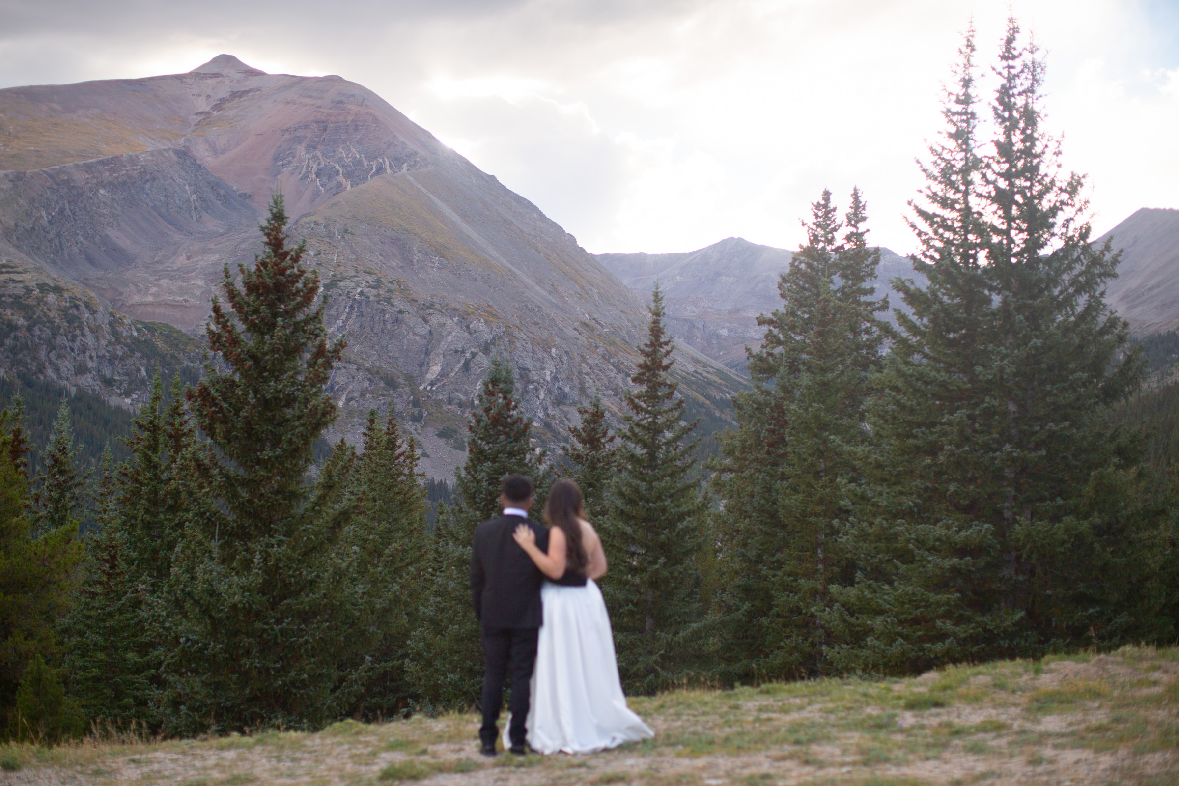 A newlywed couple runs hand in hand toward the camera, surrounded by sweeping mountain views during their adventurous Breckenridge elopement in Colorado. by Breckenridge Elopement Photographer Stephanie Eddy
